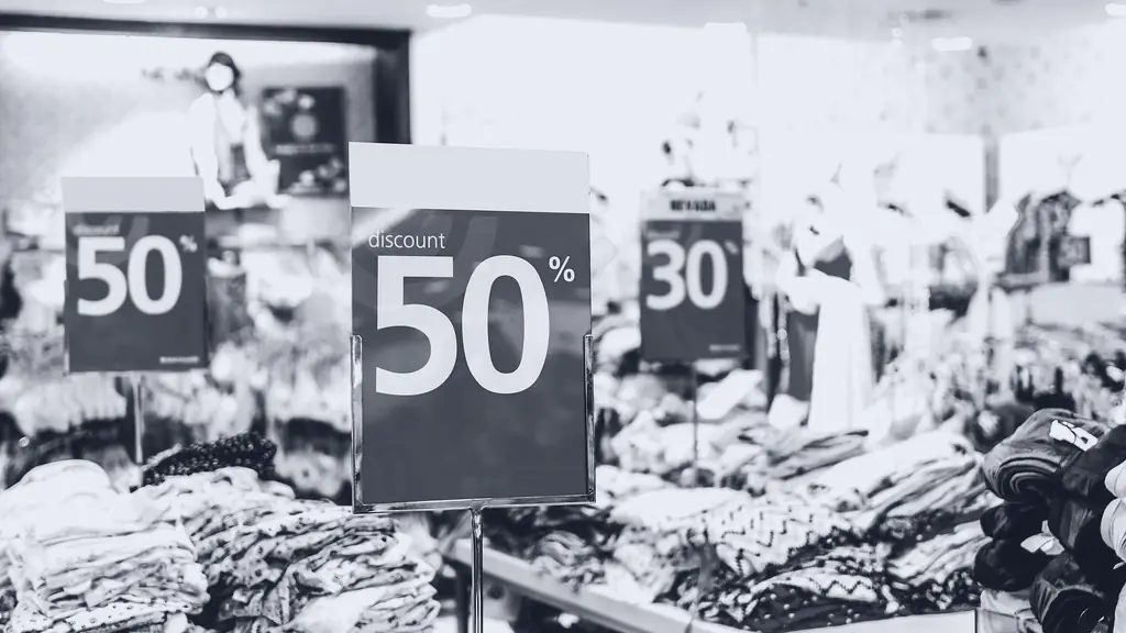 Sale signs above rails of clothes in a shop